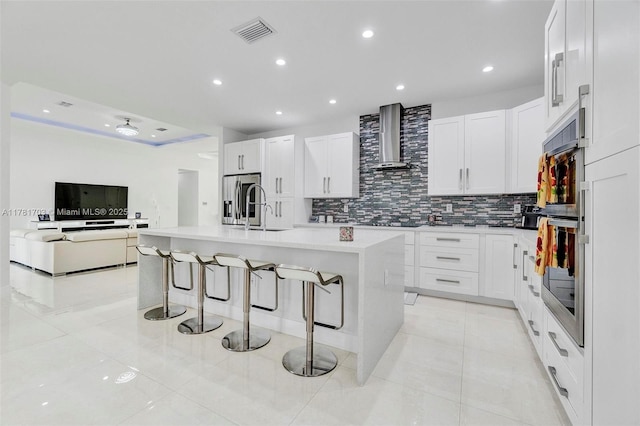 kitchen featuring visible vents, stainless steel refrigerator with ice dispenser, a sink, wall chimney range hood, and light tile patterned flooring