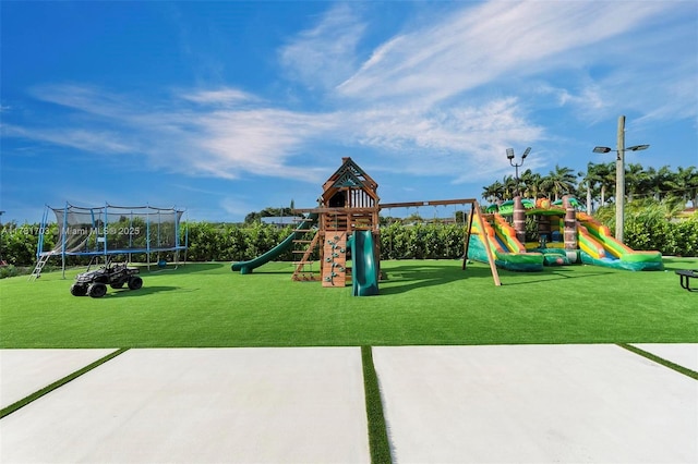 community jungle gym featuring a trampoline and a lawn