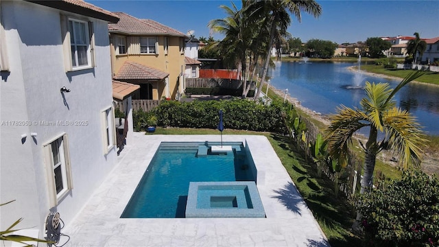view of pool featuring fence, a water view, and a pool with connected hot tub