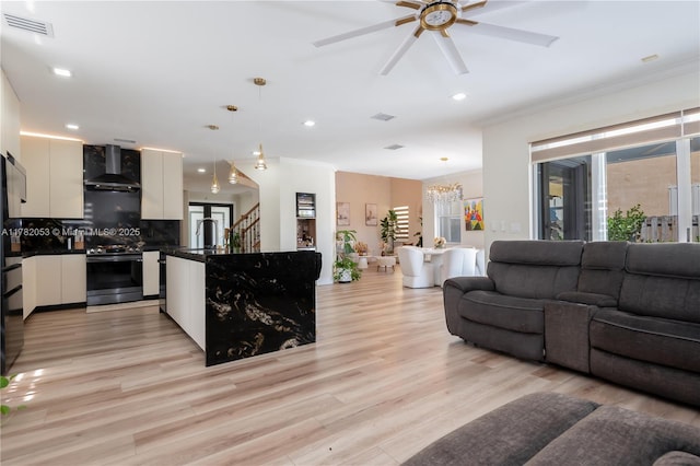 living room with crown molding, visible vents, recessed lighting, and ceiling fan with notable chandelier