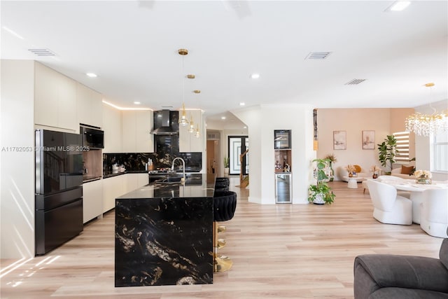 kitchen featuring visible vents, wall chimney exhaust hood, open floor plan, freestanding refrigerator, and recessed lighting