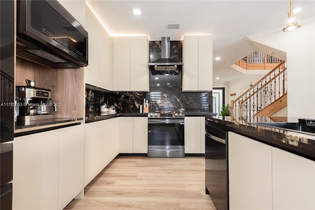 kitchen with dark countertops, black microwave, stainless steel stove, and wall chimney exhaust hood