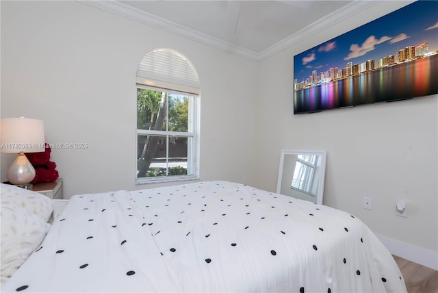 bedroom with baseboards, crown molding, and wood finished floors