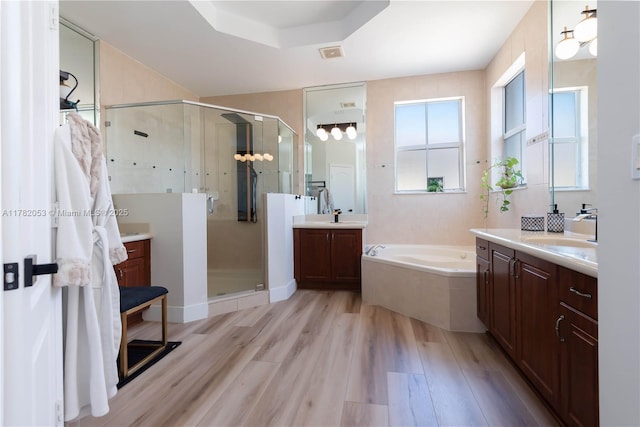 bathroom with a sink, a stall shower, wood finished floors, and a garden tub