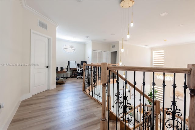 hall with baseboards, ornamental molding, an upstairs landing, visible vents, and light wood finished floors