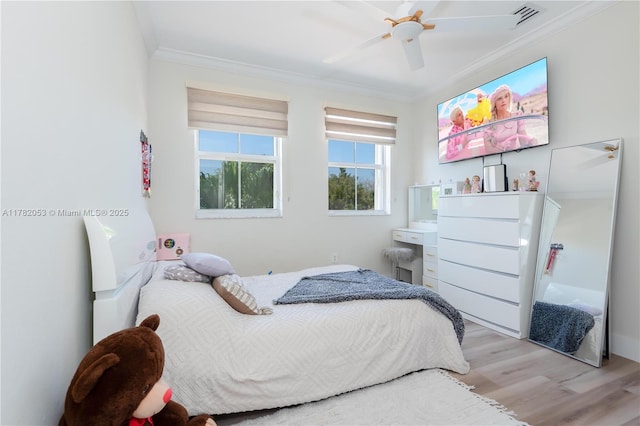 bedroom with ornamental molding, light wood-style flooring, a ceiling fan, and visible vents