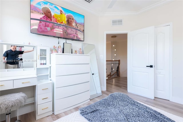 bedroom with crown molding, visible vents, light wood-style flooring, and baseboards