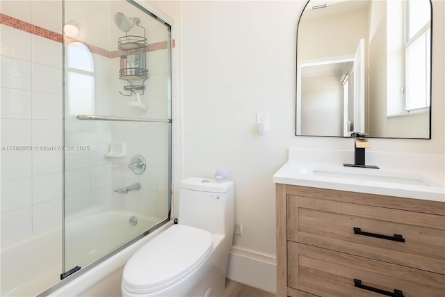 bathroom with toilet, enclosed tub / shower combo, and vanity