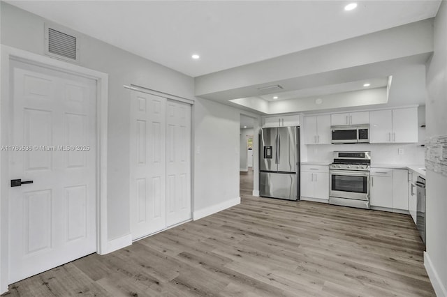 7320 Biltmore Blvd, Miramar, FL 33023 - kitchen with appliances with stainless steel finishes, light wood-style flooring, white cabinets, a raised ceiling, and light countertops