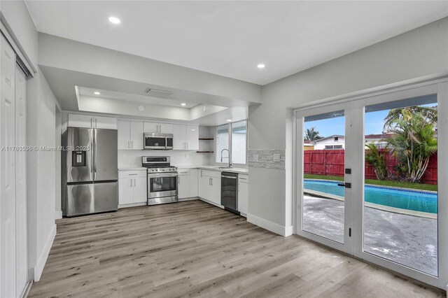 7320 Biltmore Blvd, Miramar, FL 33023 - kitchen featuring stainless steel appliances, a raised ceiling, white cabinets, light countertops, and light wood-type flooring