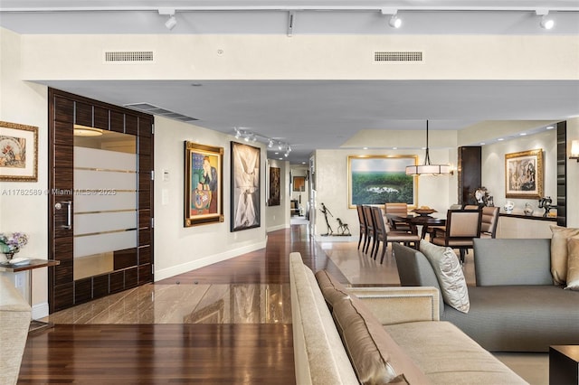living room featuring track lighting, wood finished floors, and visible vents