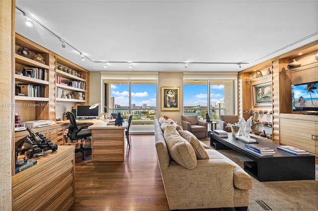 living room with track lighting, built in study area, visible vents, a healthy amount of sunlight, and wood finished floors