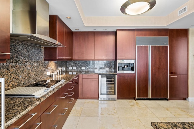 kitchen with dark brown cabinets, paneled built in fridge, visible vents, wall chimney exhaust hood, and wine cooler