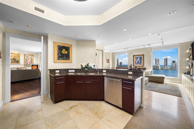 kitchen with open floor plan, visible vents, dark stone counters, stainless steel dishwasher, and a sink