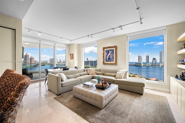living area with a water view, rail lighting, light tile patterned flooring, and a city view