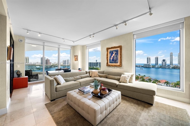 living area featuring a city view, light tile patterned flooring, rail lighting, and a water view