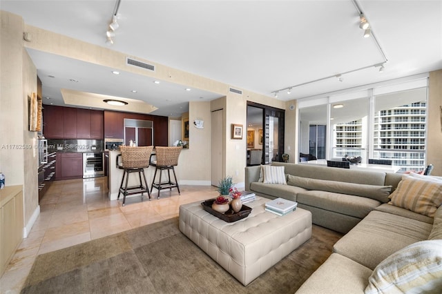 living room with track lighting, beverage cooler, visible vents, and light tile patterned floors