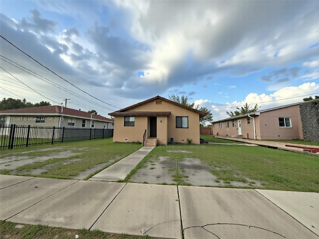 bungalow with a front lawn, fence, and stucco siding