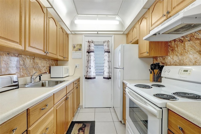 kitchen with tasteful backsplash, white appliances, light countertops, under cabinet range hood, and a sink