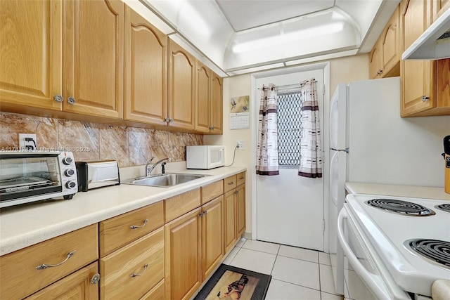 kitchen featuring light tile patterned floors, a sink, under cabinet range hood, white microwave, and backsplash