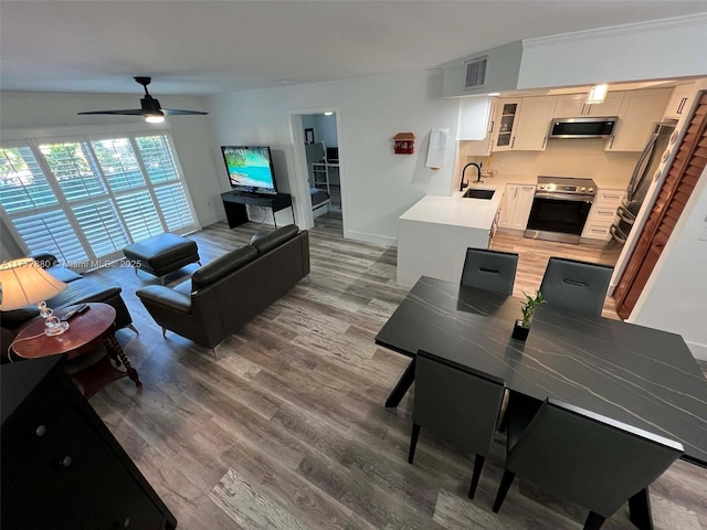 living room with visible vents, light wood-type flooring, and a ceiling fan