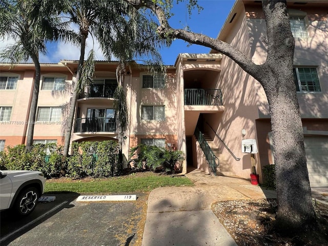 view of property featuring stairway and uncovered parking