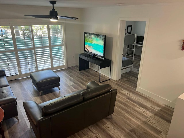 living area with baseboards, a ceiling fan, and wood finished floors