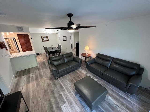 living room with visible vents, ceiling fan, wood finished floors, and baseboards
