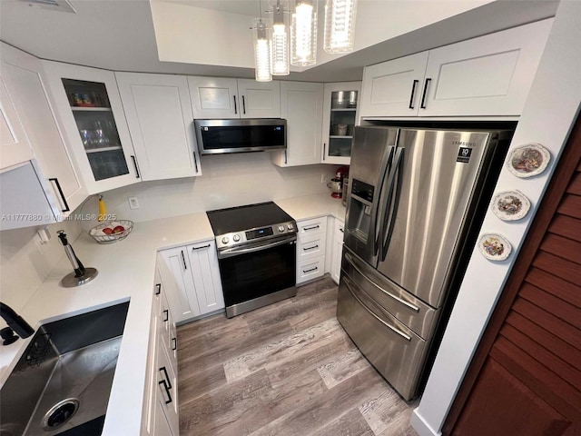 kitchen with light wood-style flooring, appliances with stainless steel finishes, light countertops, and white cabinetry