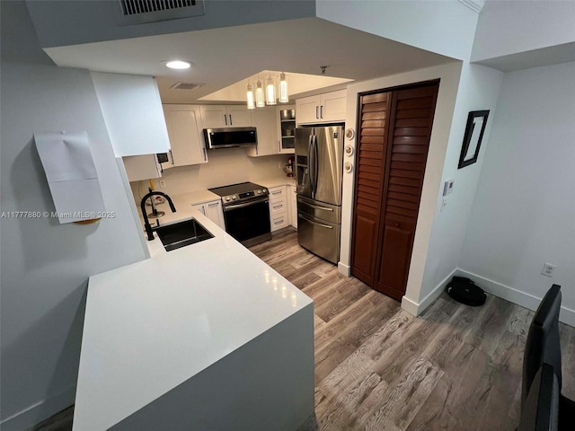 kitchen featuring visible vents, dark wood-style flooring, light countertops, a sink, and stainless steel appliances