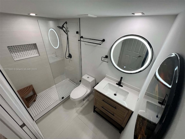 bathroom featuring toilet, a tile shower, tile patterned flooring, and vanity