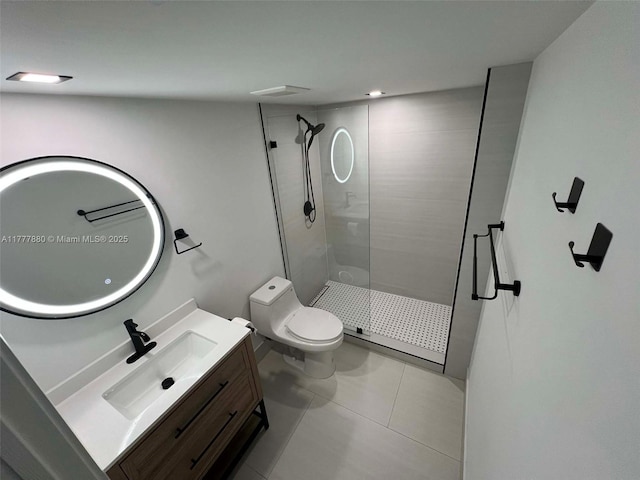 bathroom featuring toilet, tile patterned floors, a tile shower, and vanity