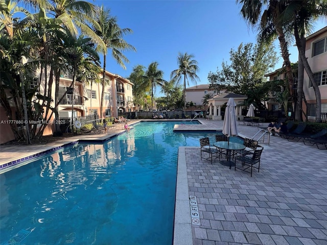 community pool with a patio and fence