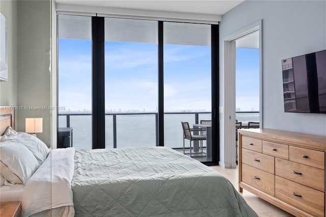 bedroom featuring expansive windows, light wood-type flooring, and a water view