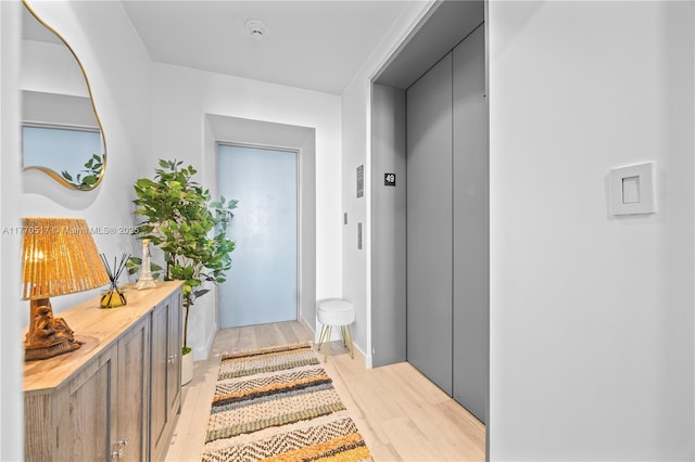 corridor featuring light wood-type flooring and elevator