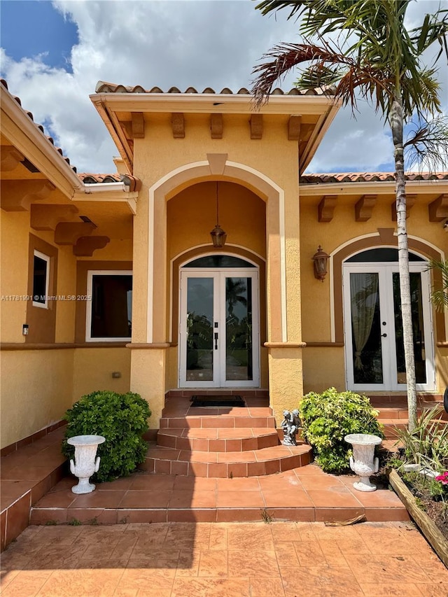 entrance to property featuring french doors, stucco siding, and a tiled roof