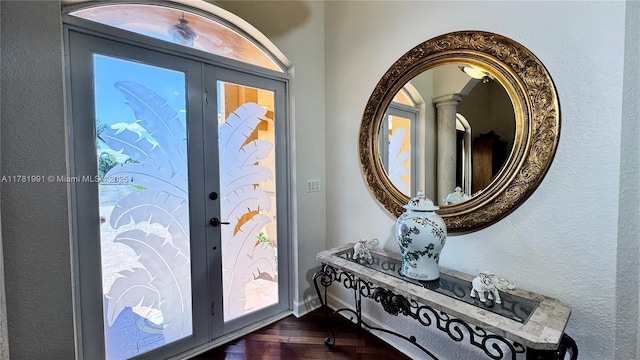 foyer featuring french doors, baseboards, a textured wall, and dark wood finished floors