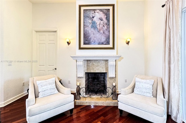 living area featuring a tiled fireplace, baseboards, and dark wood finished floors