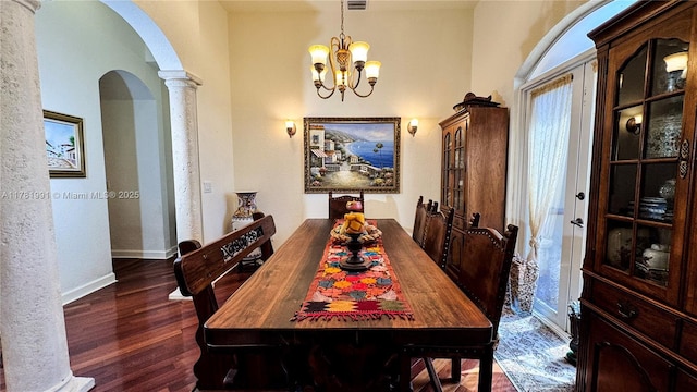 dining room featuring baseboards, arched walkways, an inviting chandelier, ornate columns, and wood finished floors
