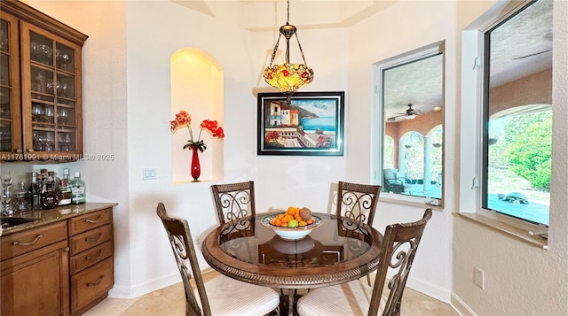 dining space featuring ceiling fan, light tile patterned floors, and baseboards