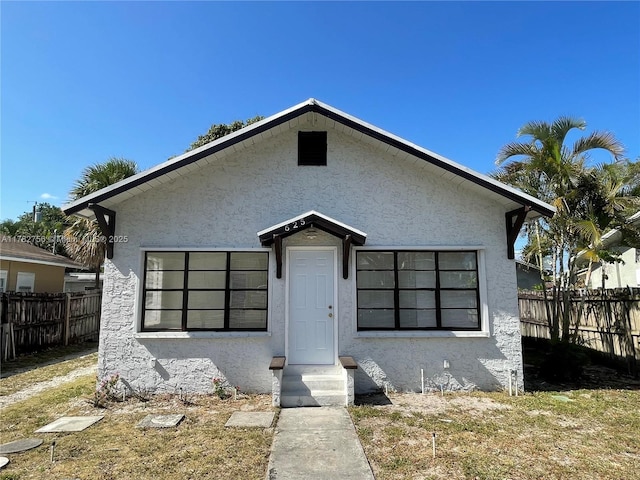 bungalow-style home featuring fence and stucco siding