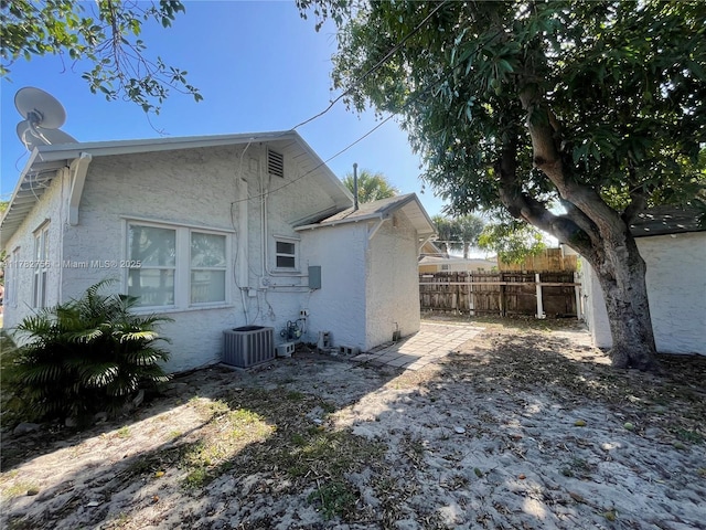 back of property with fence, central AC, and stucco siding