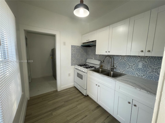 kitchen featuring a sink, dark wood-style flooring, tasteful backsplash, under cabinet range hood, and white gas range