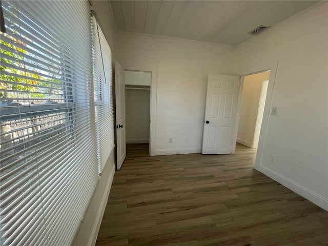 unfurnished bedroom featuring visible vents, baseboards, wood finished floors, a closet, and a walk in closet