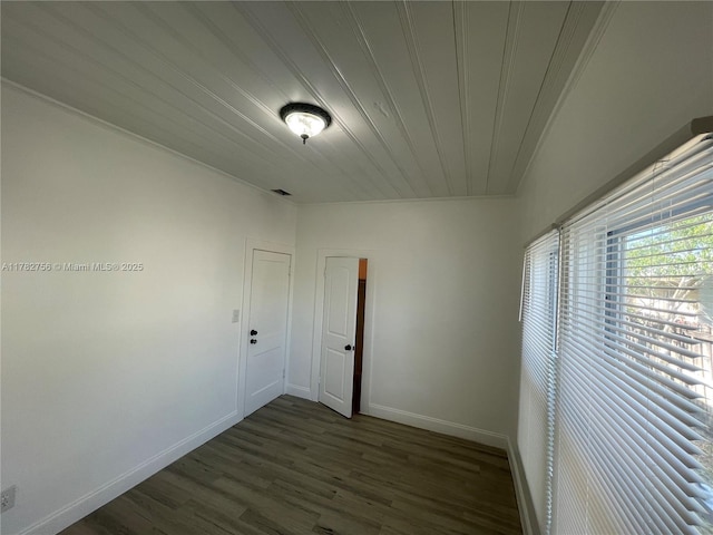 spare room with baseboards, dark wood-style floors, and ornamental molding