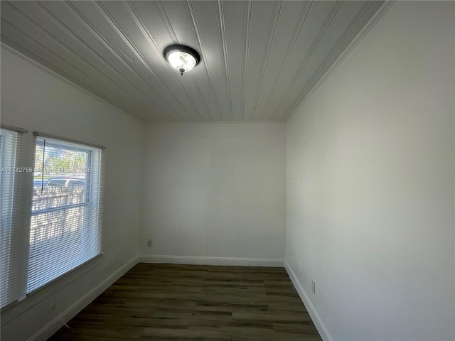 empty room with dark wood finished floors, baseboards, crown molding, and wooden ceiling