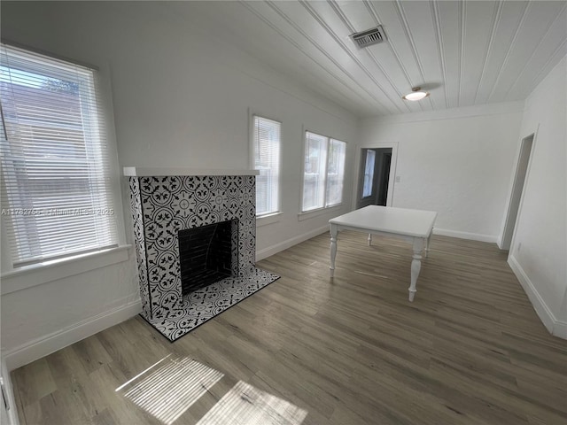 unfurnished living room featuring baseboards, wood finished floors, visible vents, and a tiled fireplace