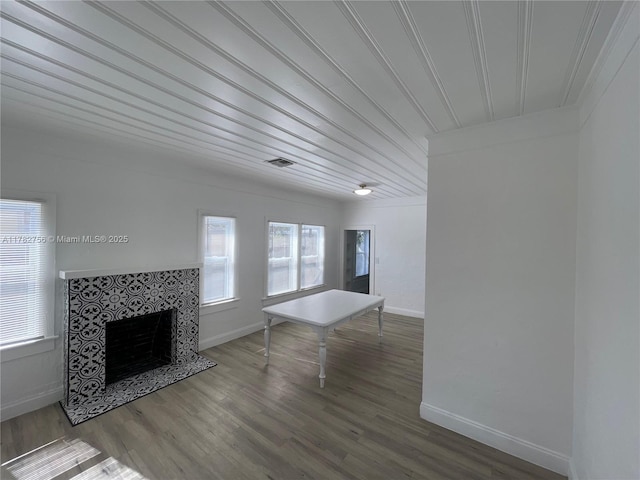 unfurnished living room with a fireplace, wood finished floors, visible vents, and baseboards