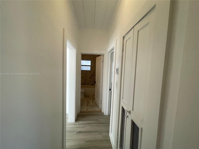 corridor with wood finished floors and ornamental molding