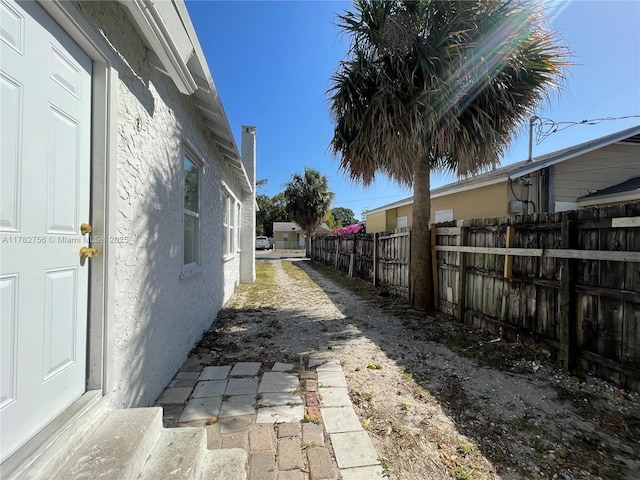 view of side of property featuring fence and stucco siding